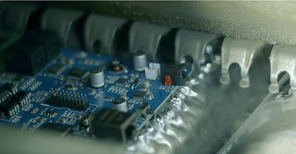 Blue printed circuit board passing through soldering stage in pcba manufacturing.