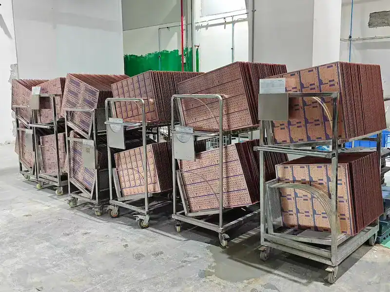 PCB panels on stainless steel transport racks during production staging between fabrication steps