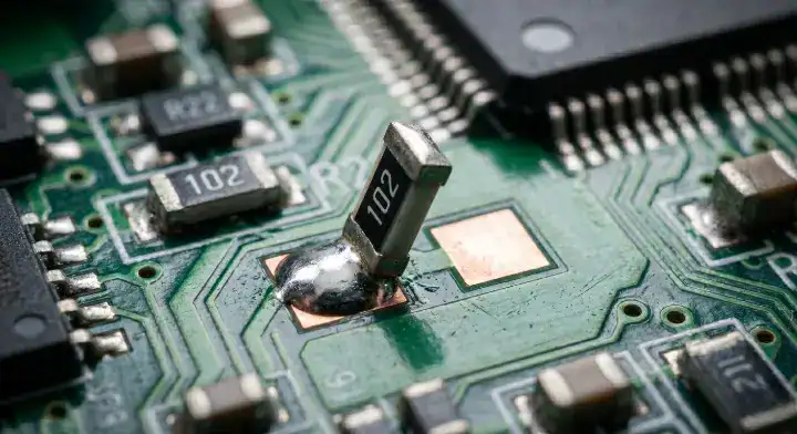Extreme macro view of a tombstoning defect on a surface mount resistor, highlighting failures that require you to reduce PCB assembly rework cleanup