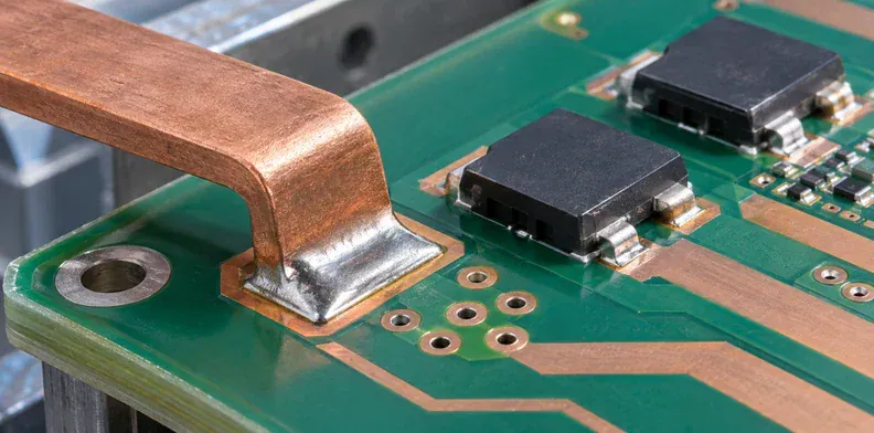 Local copper lands and via groups connect a busbar tap to power devices on a green board.