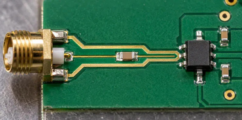 A thin exposed conductor follows a short input trace between a connector and amplifier.